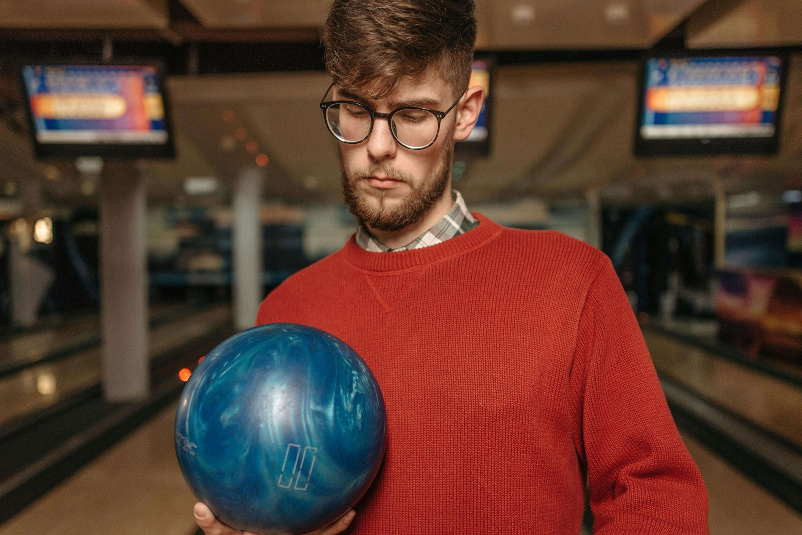 man looking down at a blue bowling ball