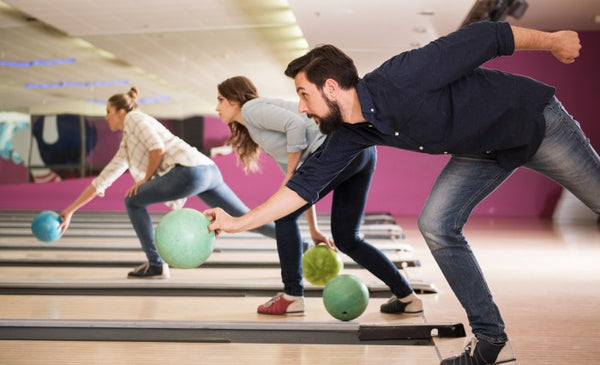 Three people rolling a bowling ball