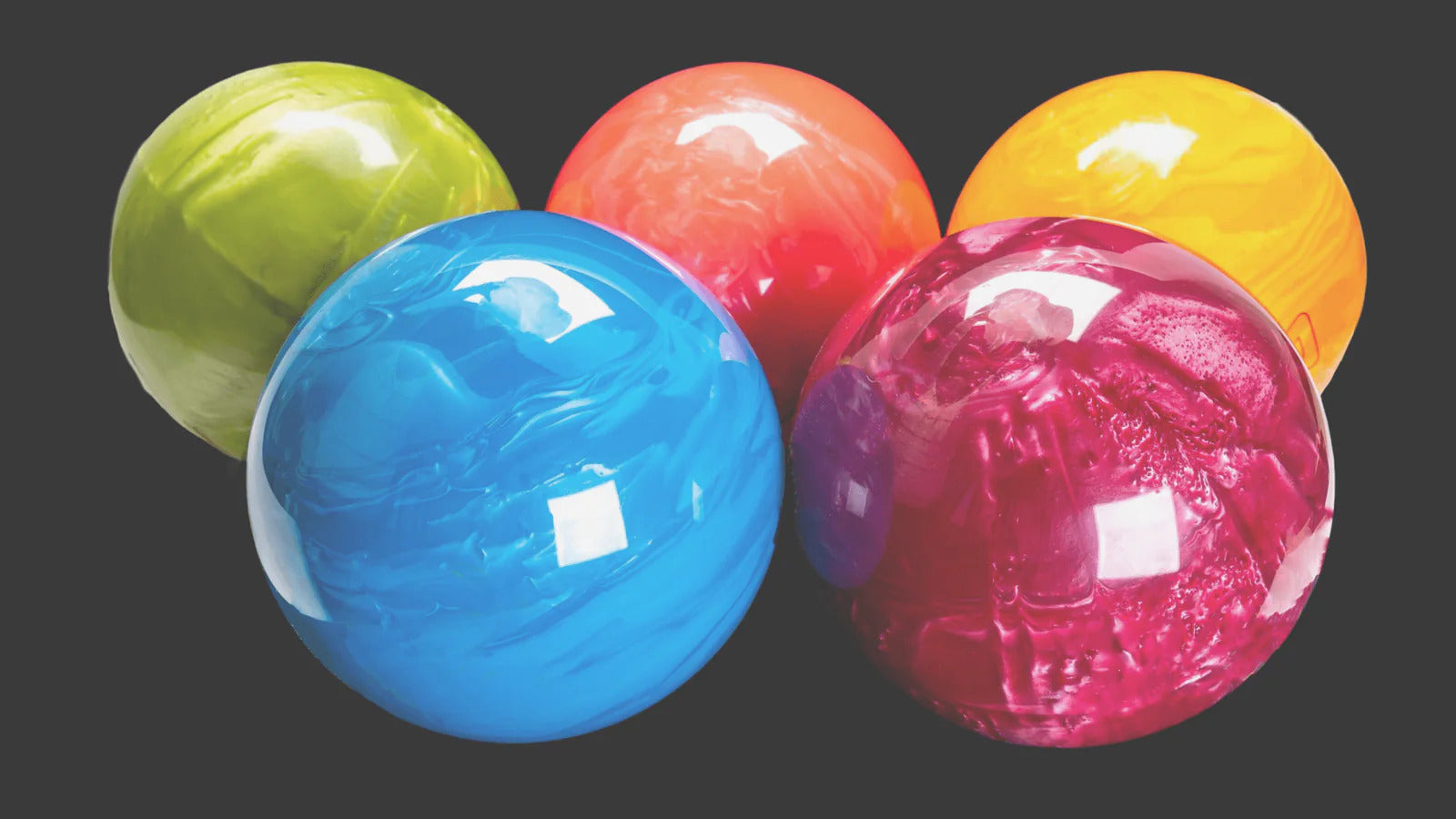 A lineup of five shiny bowling balls of different colors with a plain, dark background