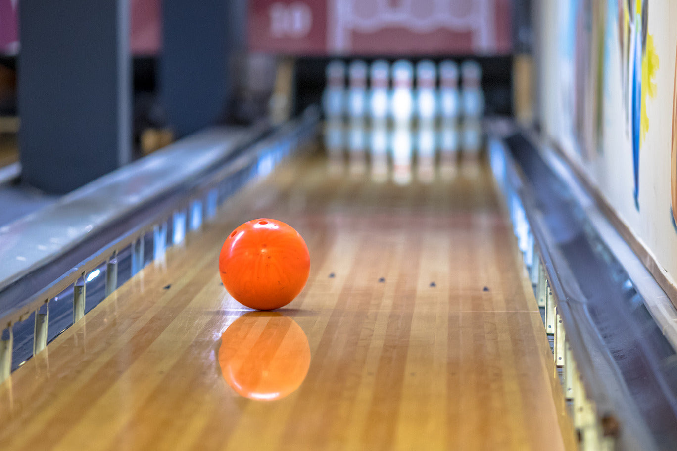 A bowling ball rolling down a lane to the pins
