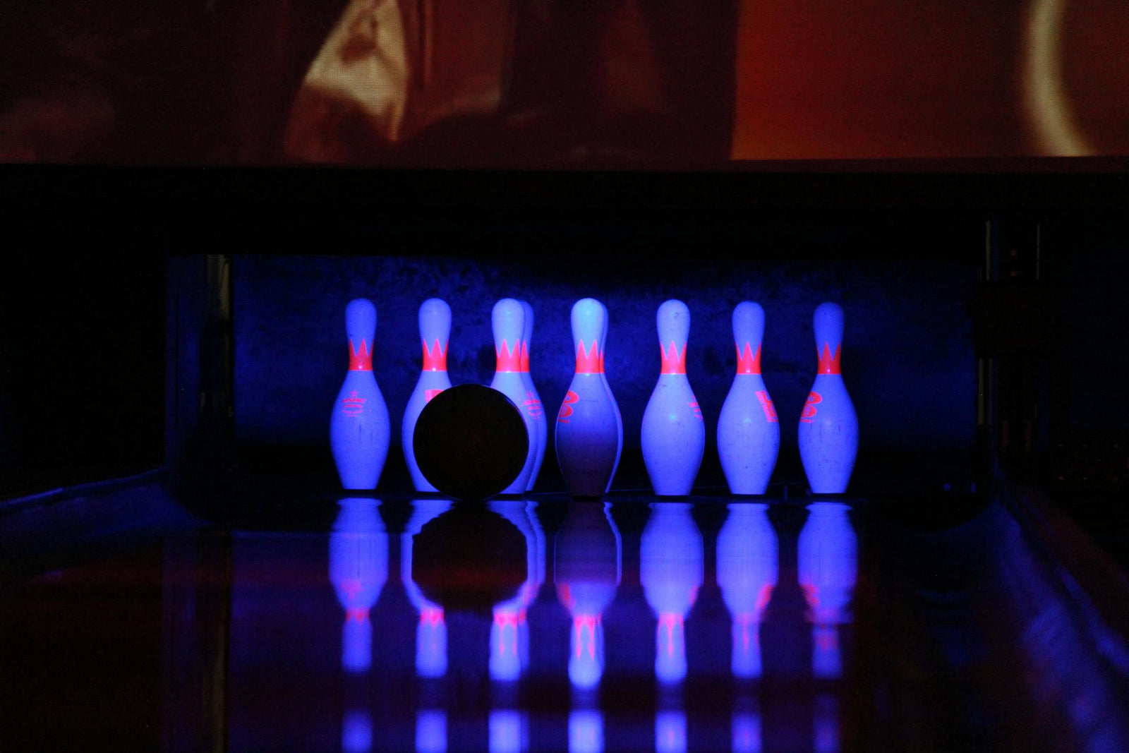 Bowling pins and a bowling ball illuminated by neon lights