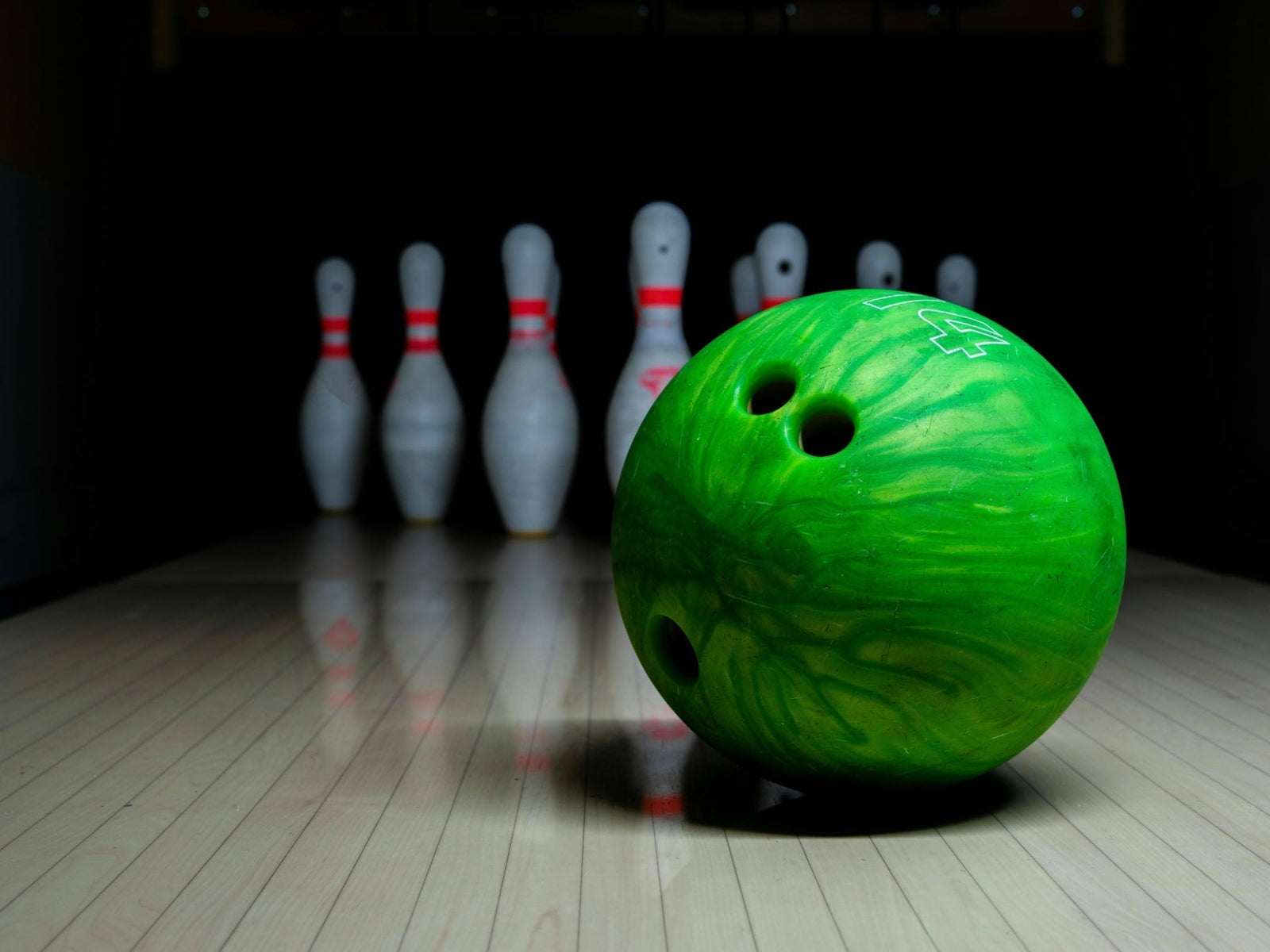 green bowling ball in front of pins
