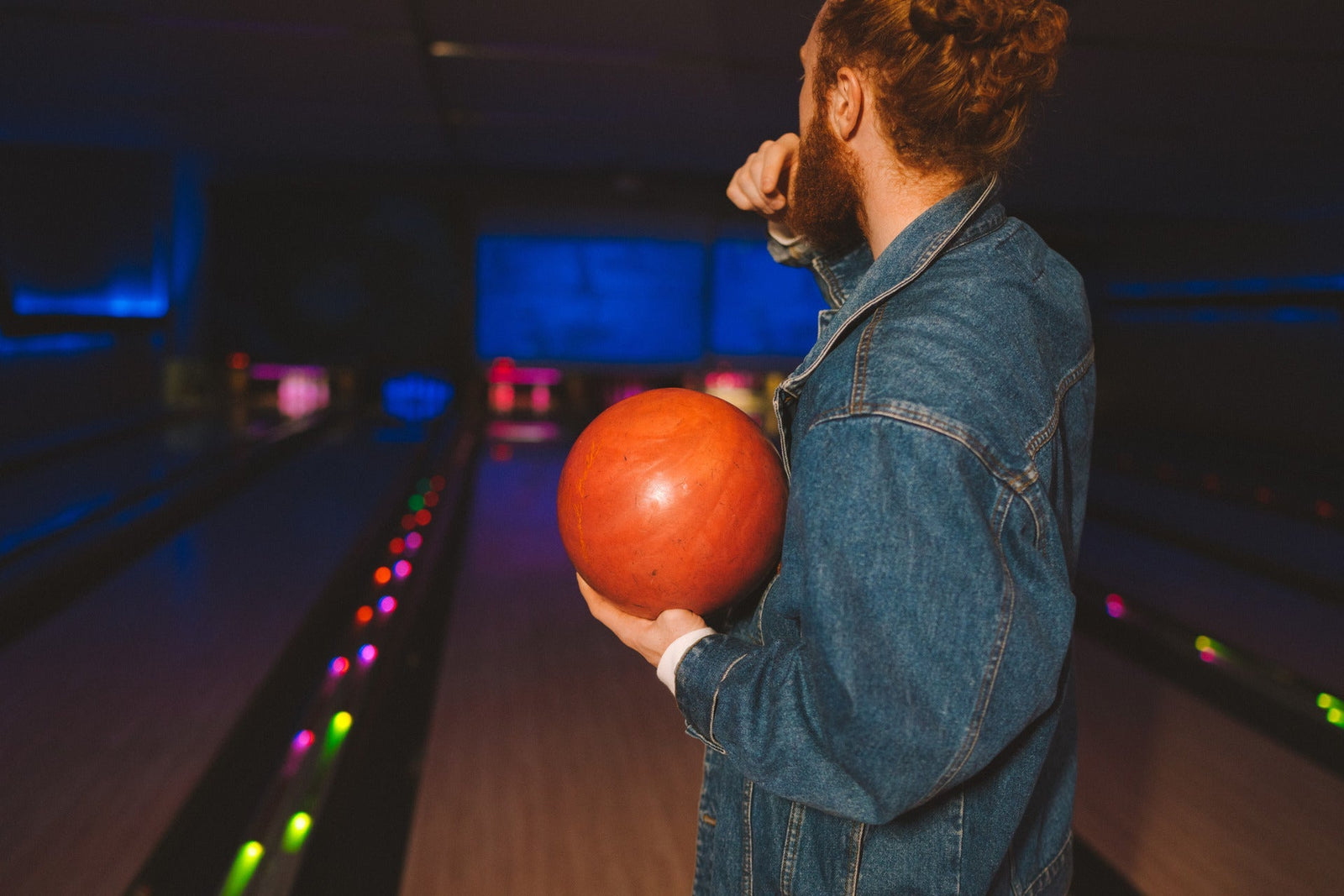 man holding an orange bowling ball