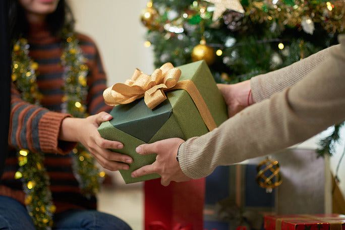 two people exchanging a wrapped gift